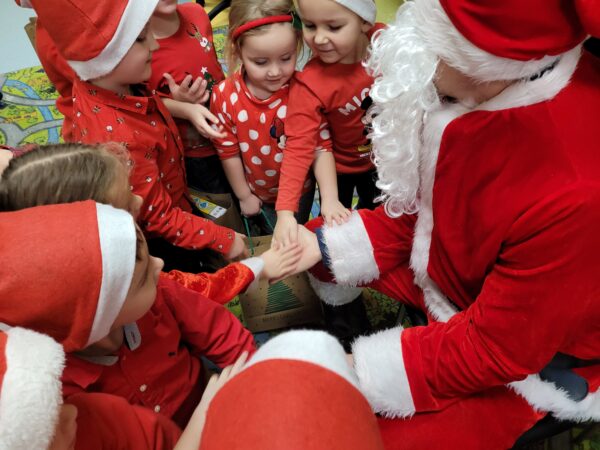 Dzieci przybijają piątki Mikołajowi.
