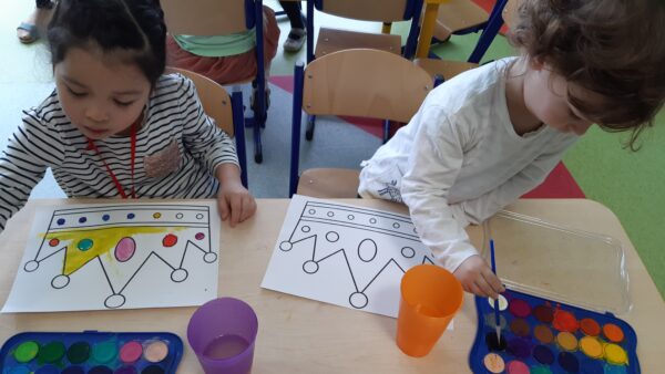 Mia i Ignaś malują farbami akwarelowymi szablon korony