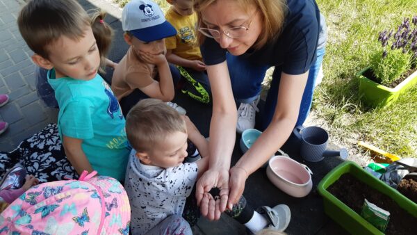 Wychowawca pokazuje dzieciom nasionka szczypiorku