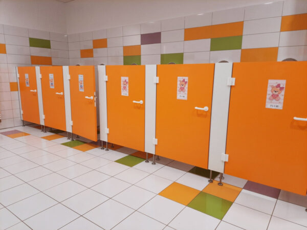 Wnętrze sanitariatów dla dzieci przedstawiające szereg kabin z toaletami
