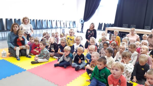 Dzieci słuchają książki czytanej przez dyrektora przedszkola, Oleńkę i Olka