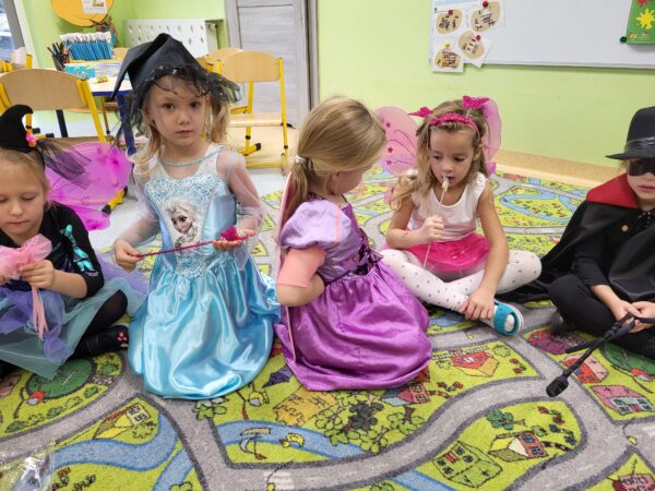 Dziewczynki Hela, Amela i Lusia siedza na dywanie.