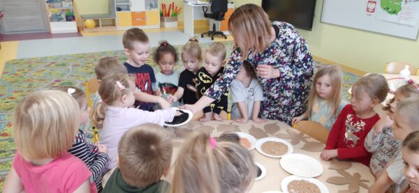 Wychowawca pokazuje dzieciom ziarenka czarnuszki i czarnego sezamu
