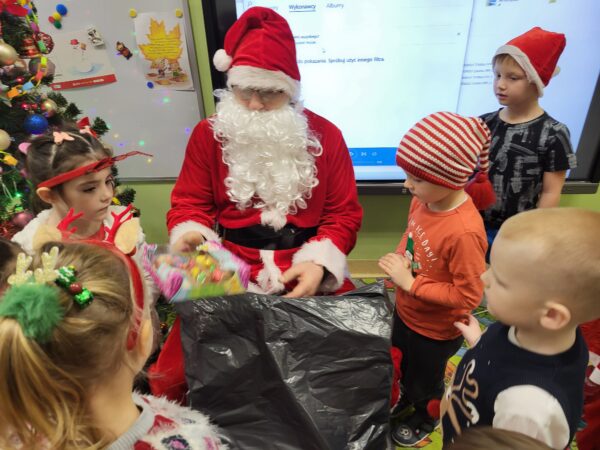 Dzieci odbierają prezenty od Mikołaja.
