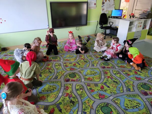Dzieci siedzą w kole i podziwiają swoje dinozaury.