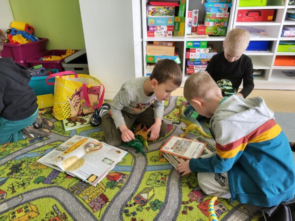 Dzieci oglądają książki o dinozaurach.no