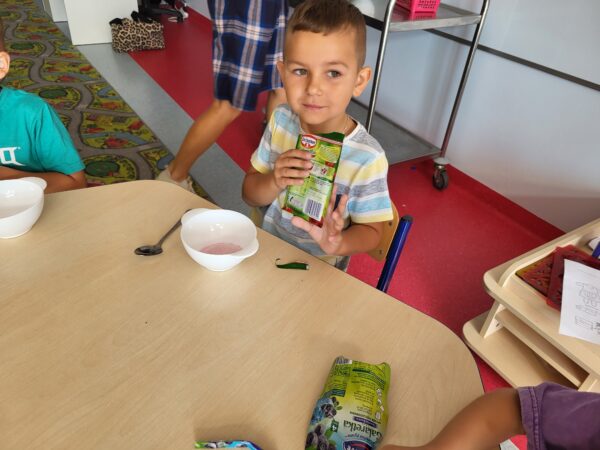 Dzieci przy stolikach mieszają galaretkę.