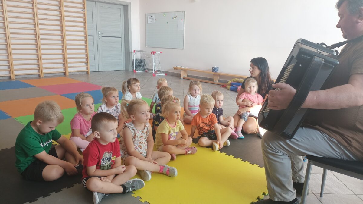 Dzieci słuchają jak pan Andrzej gra na akordeonie