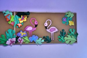 Wisząca na ścianie tablica korkowa ozdobiiona flamingami i motywami roślinnymi