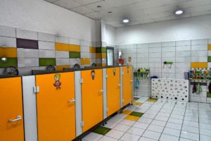 Wnętrze sanitariatów dla dzieci przedstawiające szereg kabin z toaletami