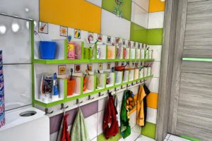 Wnętrze sanitariatów dla dzieci przedstawiające półki z kubkami i szczoteczkami do zebów oraz wieszaki na ręczniki