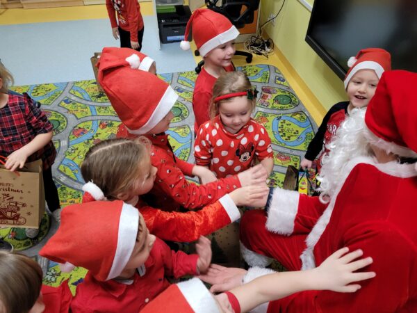 Dzieci przybijają piątki Mikołajowi.