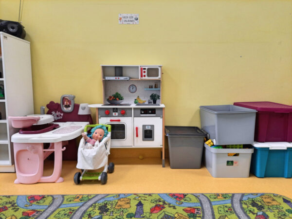 Kącik zabaw z wózkiem dla lalek , zabawkowąkuchnią oraz pojemniki z zabawkami