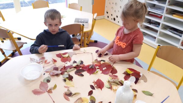 Dzieci wyklejają kontur jeża kolorowymi listkami