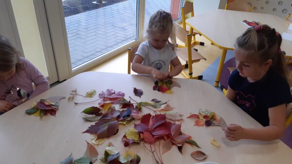 Dzieci wyklejają kontur jeża kolorowymi listkami