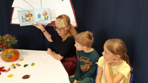 Dyrektor przedszkola razem z Oleńką i Olkiem czytają wszystkim przedszkolakom książkę w ramach obchodów Ogólnopolskiego Dnia Głośnego Czytania