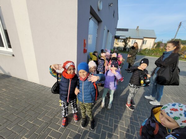 Dzieci stoja ustwione w parach przed przedszkolem .