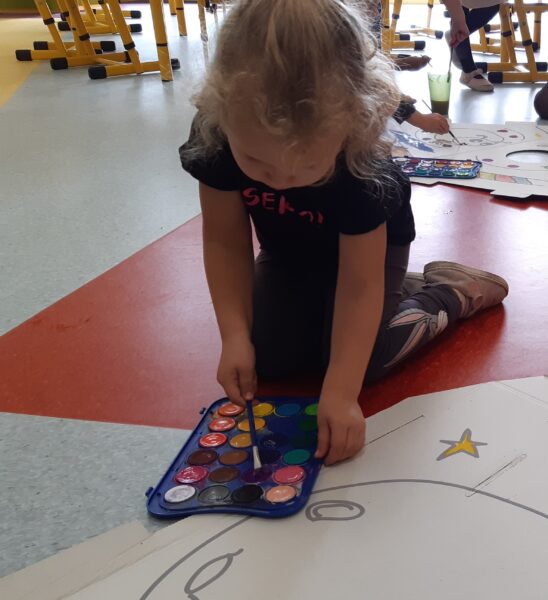 Kamilka maluje akwarelami makietę rakiety kosmicznej