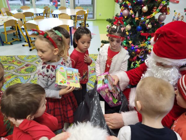 Dzieci odbierają prezenty od Mikołaja.