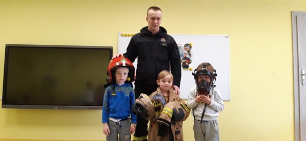 Michałek, Igorek i Franek przymierzają elementy wyposażenia ubrania bojowego ratowniczo-gaśniczego