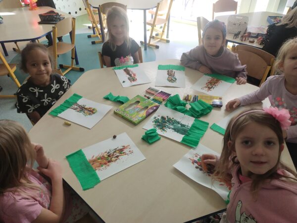 Dziewczynki dekorują drzewa plasteliną i bibułą