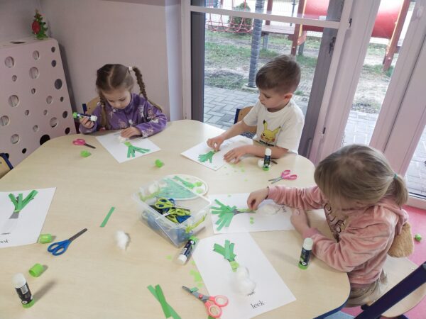 Przedszkolaki przyklejają liście pora