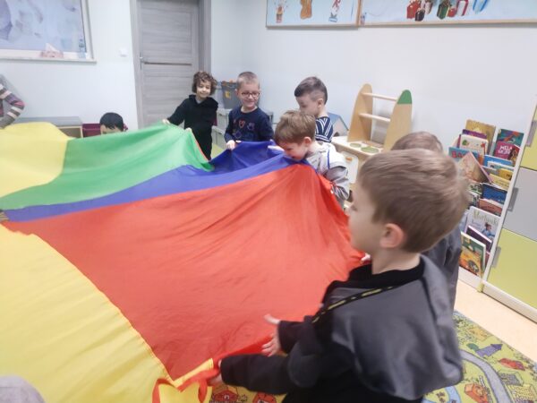 Podczas gdy dwie osoby przebiegają pod chustą pozostali powtarzają głośno określony kolor w języku angielskim