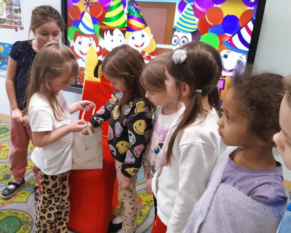 Karolcia rozdaje dzieciom urodzinowe słodkości.