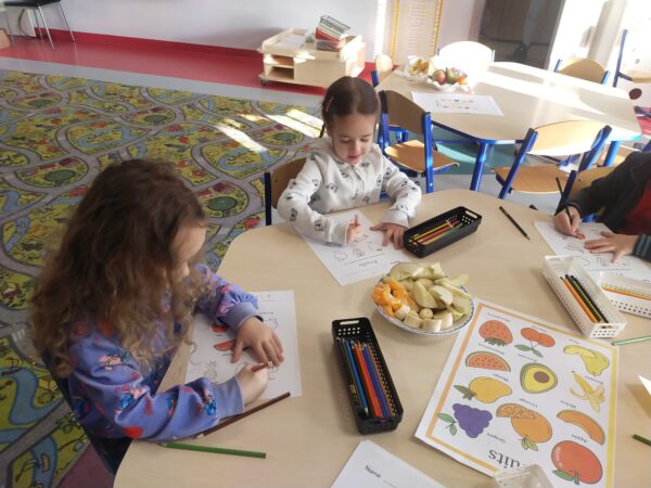 Dziewczynki kończą kolorować owoce w oczekiwaniu na degustację