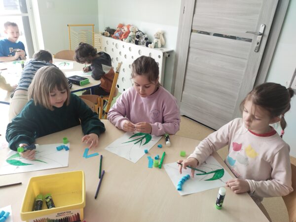 Przedszkolaki przyklejają kwiaty szafirka