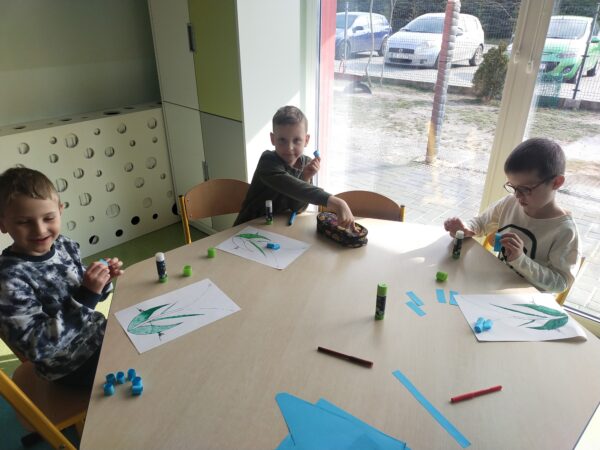 Chłopcy z kawałków kolorowego papieru tworzą pąki wiosennych kwiatów