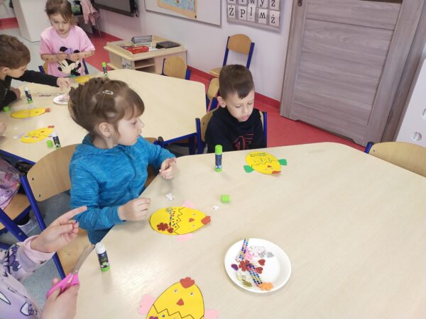 Dzieci przyklejają grzebień i skrzydełka kurczaczka