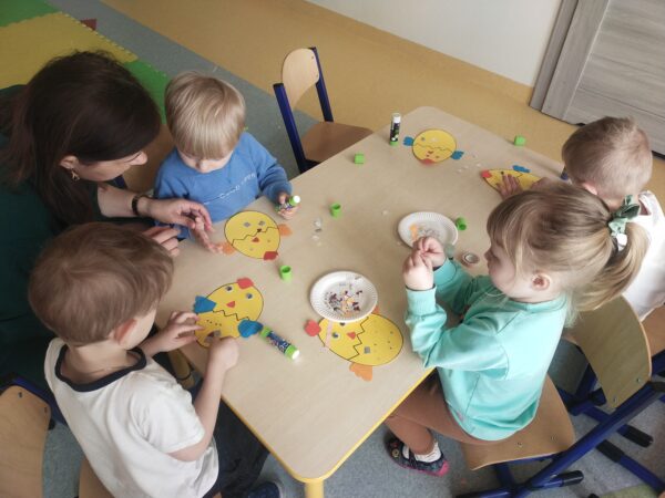 Przedszkolaki przyklejają kolorowe ozdoby