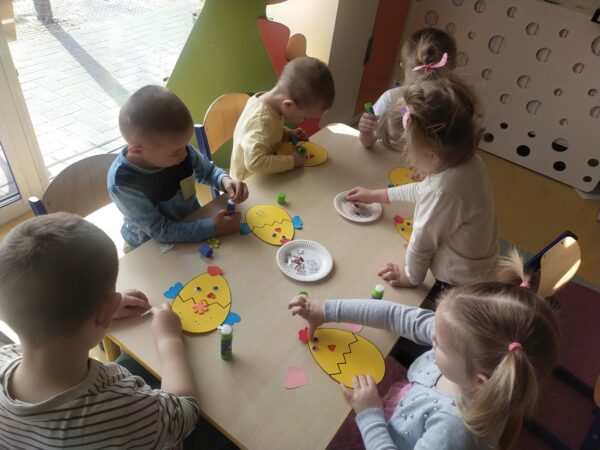 Dzieci przyklejają oczy i nos kurczaczka