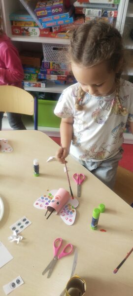 Eliza ozdabia kolorowymi kropkami skrzydła motyla