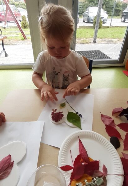 Klarcia ozdabia serduszko materiałem przyrodniczym.