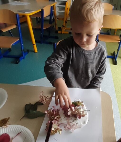 Iwo ozdabia serduszko materiałem przyrodniczym.