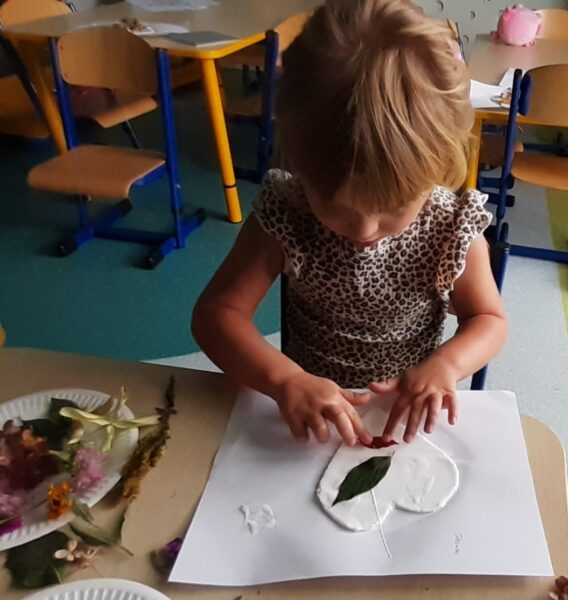 Darusia ozdabia serduszko materiałem przyrodniczym.