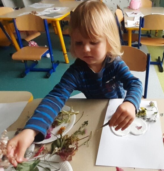 Rysio ozdabia serduszko materiałem przyrodniczym.