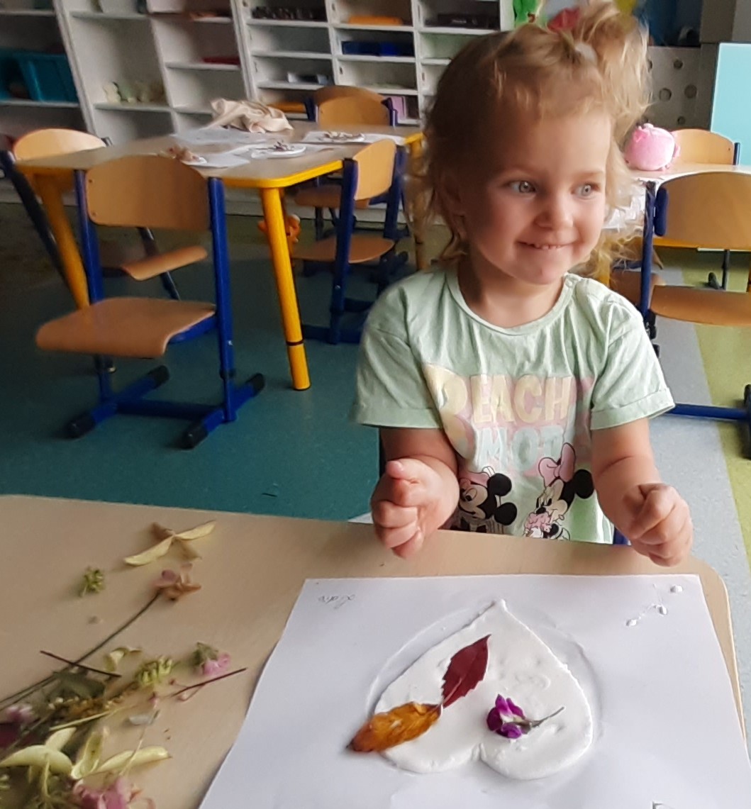 Lidzia ozdabia serduszko materiałem przyrodniczym.