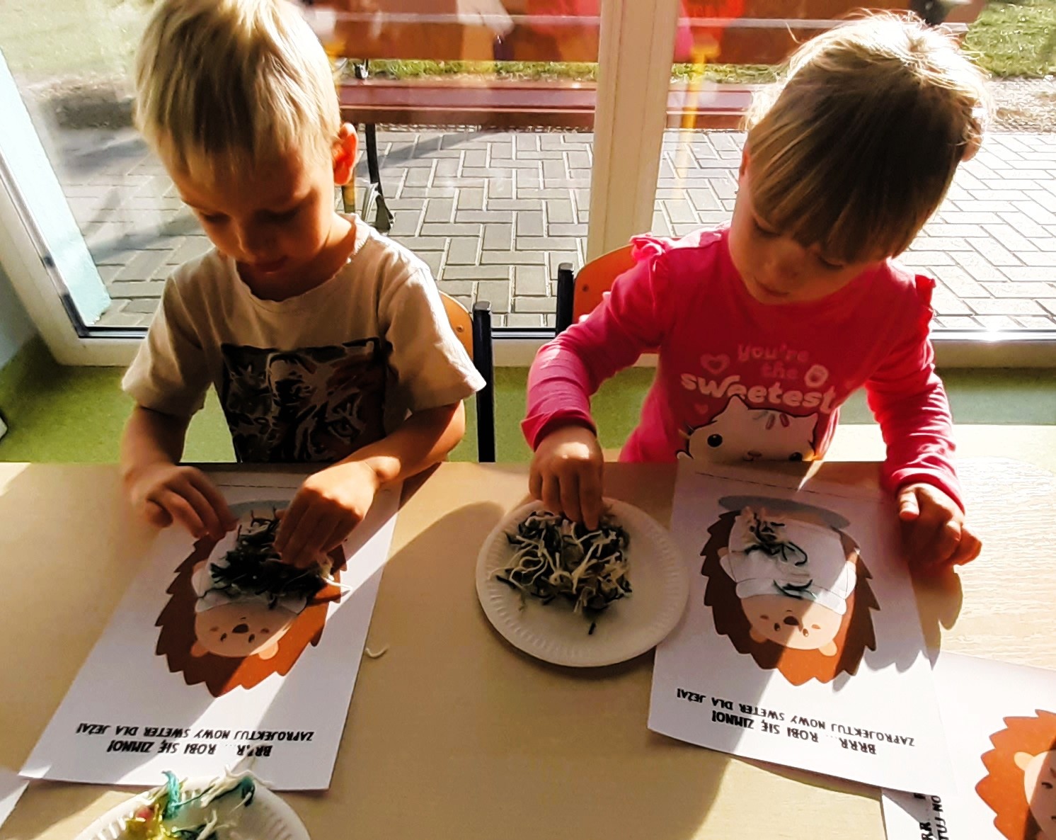 Misie wykonują pracę plastyczną z wykorzystaniem różnorodnych faktur włóczki.